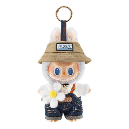 White monster character keychain with bunny ears, bucket hat, denim overalls, holding a white daisy