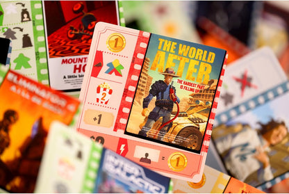 Close-up of board game cards. The central card, "The World After," depicts a man fueling a post-apocalyptic vehicle in a desert