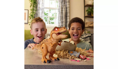 Two excited boys watch a toy T-Rex with glowing orange eyes standing beside a cracked dinosaur egg and remote control on a table