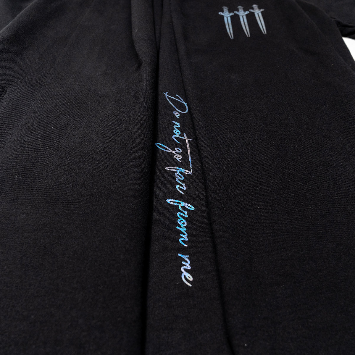 Black Vax'ildan hooded cloak with iridescent vertical text "Do not go far from me" and three dagger icons