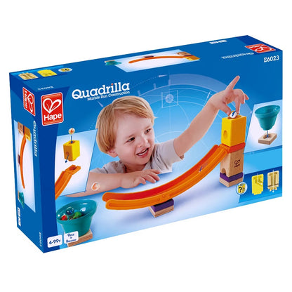 Hape Quadrilla Marble Run toy box. A smiling child drops a marble onto the orange curved track