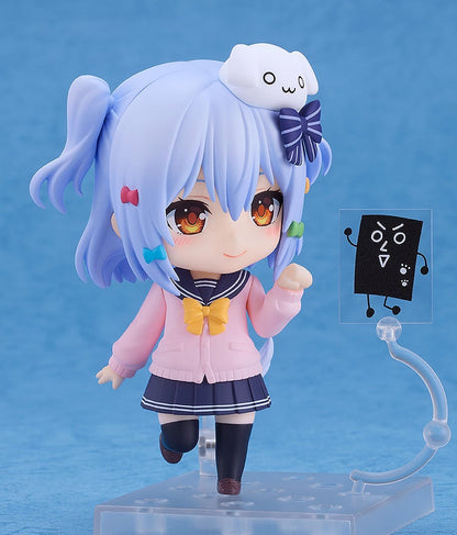 Smiling Nendoroid figure of an anime girl with light blue hair in pigtails, wearing a pink cardigan over a navy school uniform, posing with a black sign