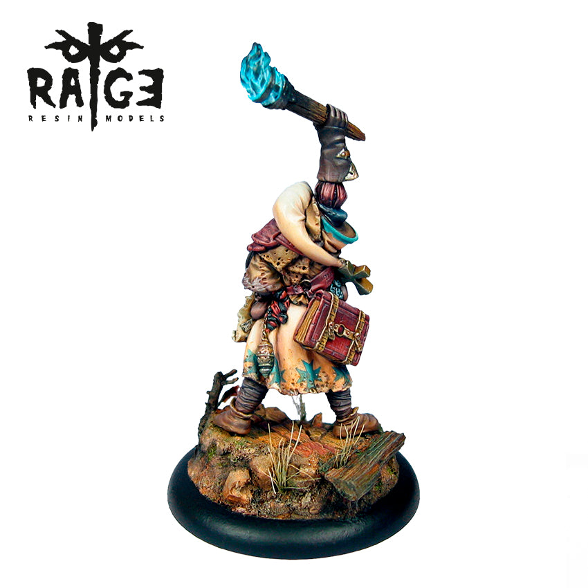 Painted miniature of a hooded figure holding a glowing blue torch, carrying a book, standing on a detailed rocky base