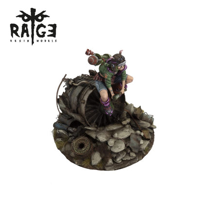 A miniature female figure with goggles and a booster pack crouches on a destroyed jet engine amidst rubble, holding a tool