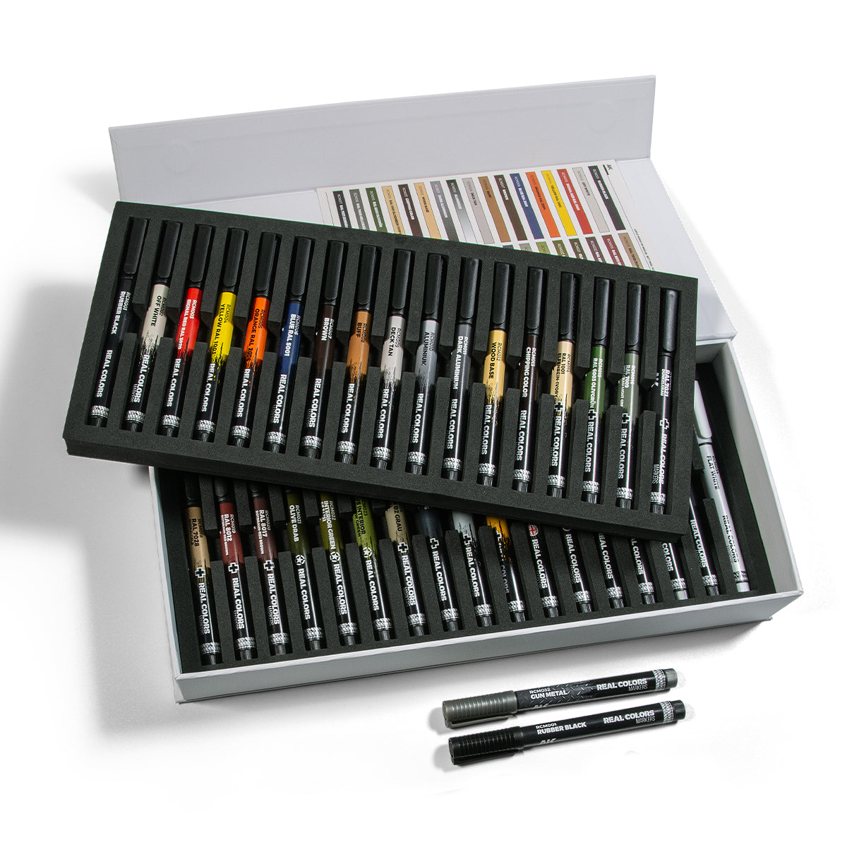 An open white box containing 34 Real Colors Markers in foam trays, with a color chart in the lid and two markers lying beside it