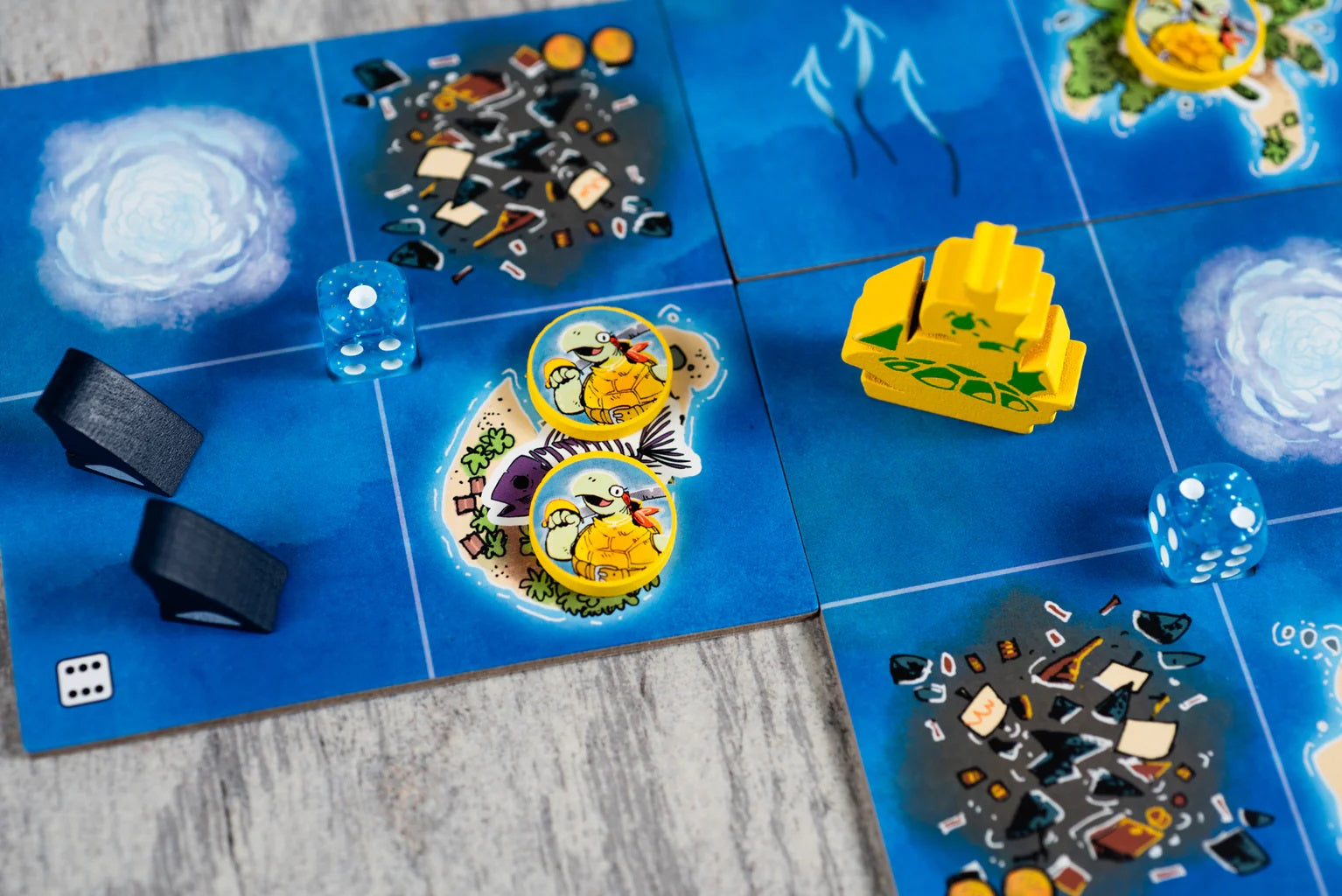 Yellow wooden ship and turtle tokens on a blue board game map showing ocean, dice, and storm graphics