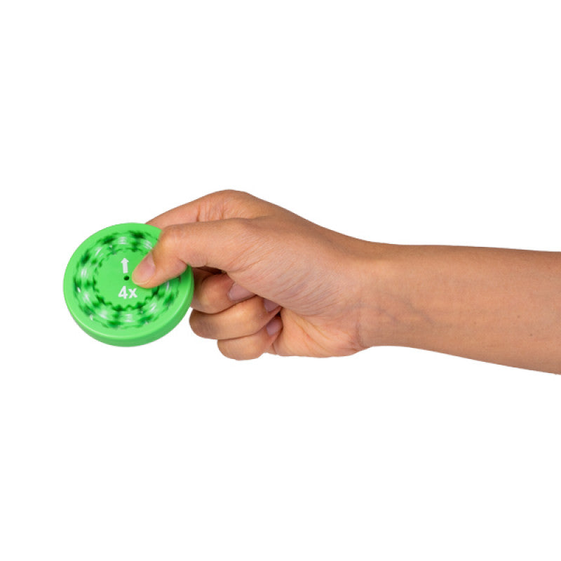 Hand holding a green fidget spinner with a white arrow indicating direction and 4x