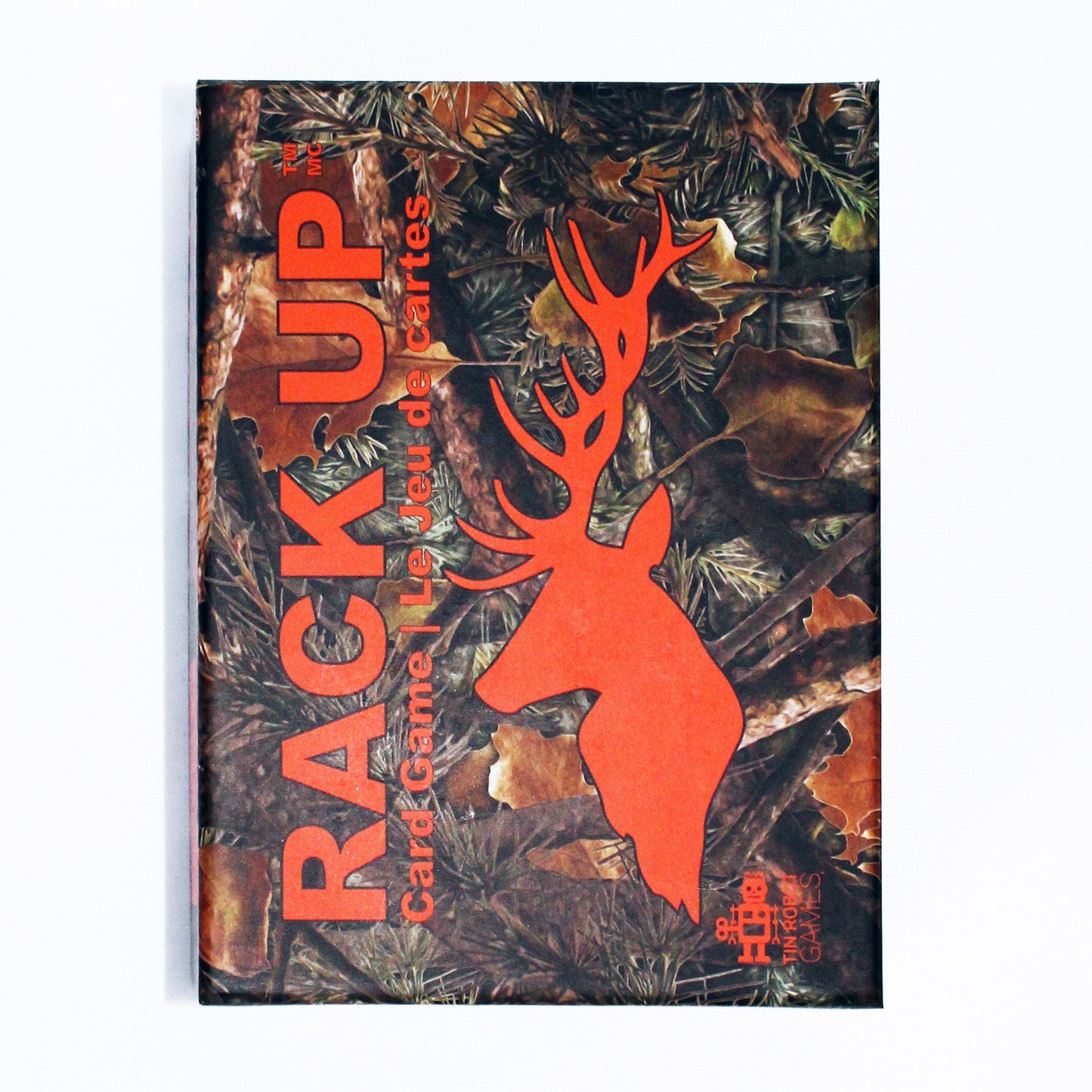 A hunting card game box titled Rack Up featuring a camouflage pattern with leaves, pine needles, and an orange deer silhouette