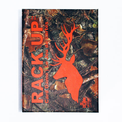 A hunting card game box titled Rack Up featuring a camouflage pattern with leaves, pine needles, and an orange deer silhouette