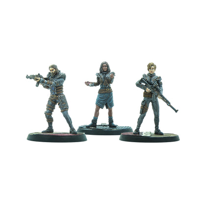 Three character miniatures: a man aiming a rifle, a woman holding tech devices, and another woman carrying a rifle