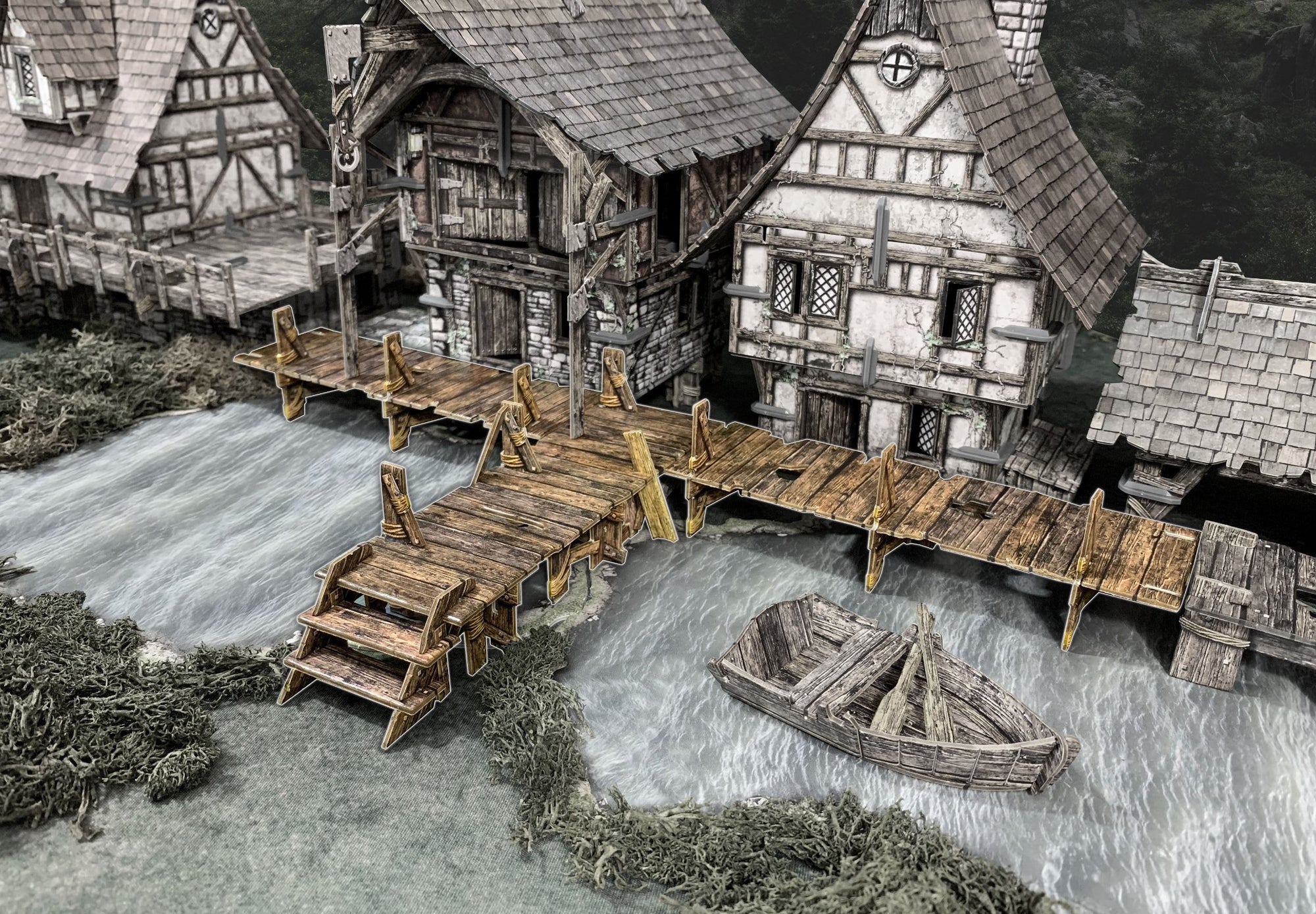 Detailed miniature of a medieval-style riverside village with timber-framed buildings, wooden docks, and a rowboat.