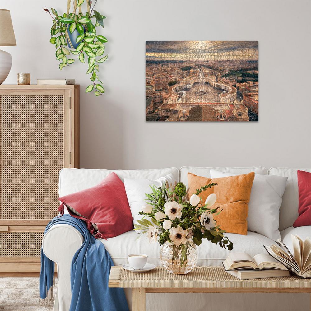 A jigsaw puzzle depicting an aerial view of St. Peter&#39;s Square hangs above a white sofa in a living room