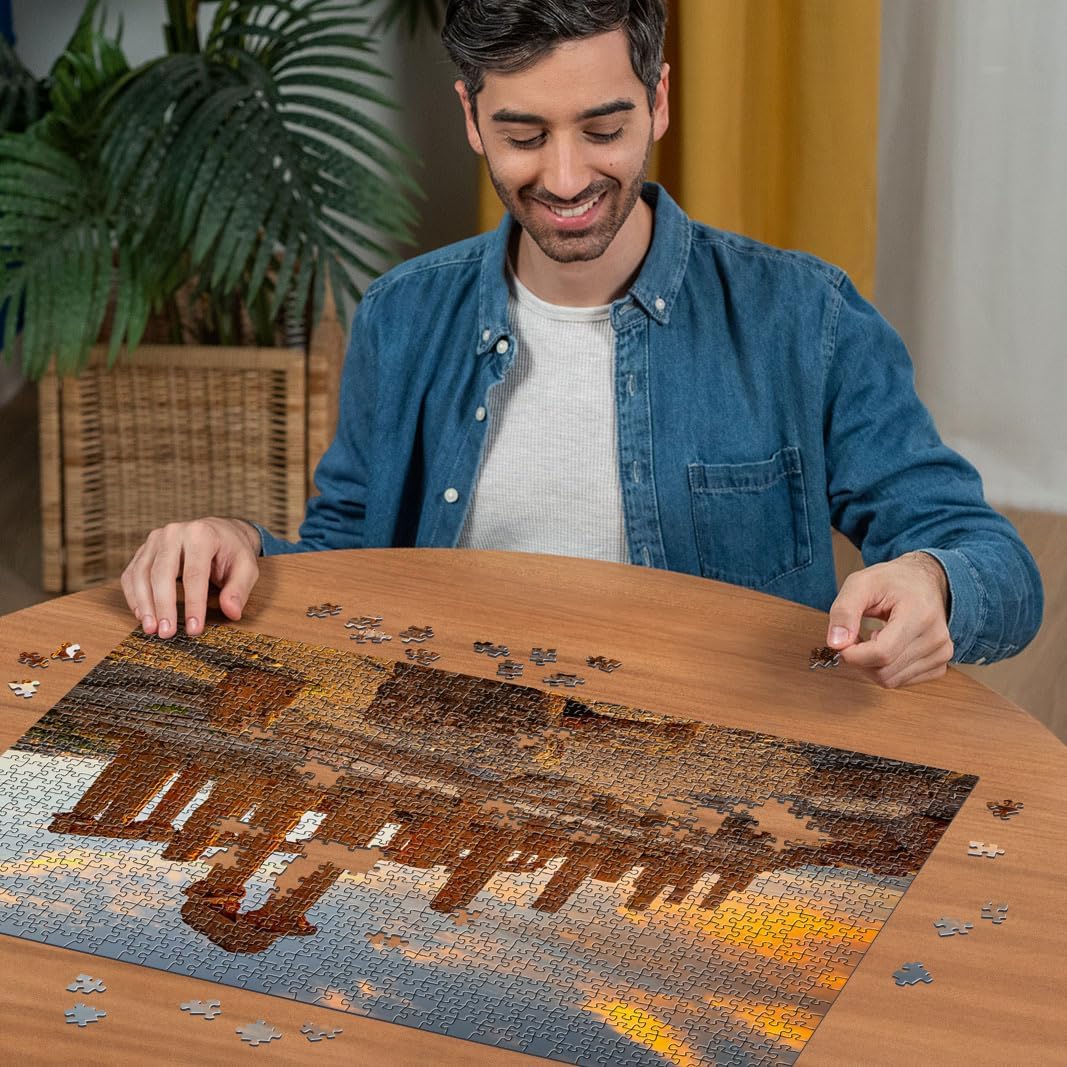 Smiling man in blue shirt assembling a colorful Ravensburger Valley of the Temples Agrigento 1000-Piece Jigsaw puzzle