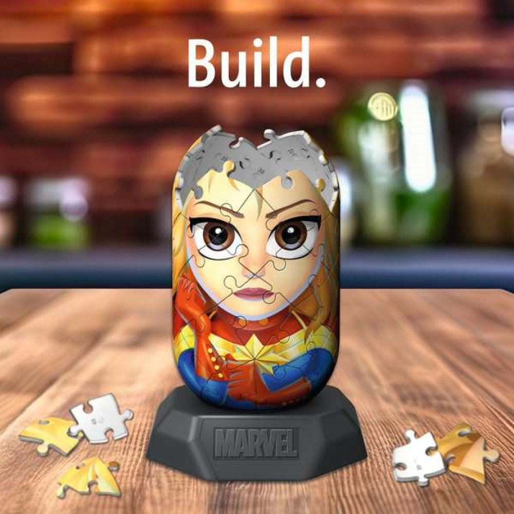 Partially built 3D Captain Marvel puzzle on a Marvel base, with loose pieces. Text: Build