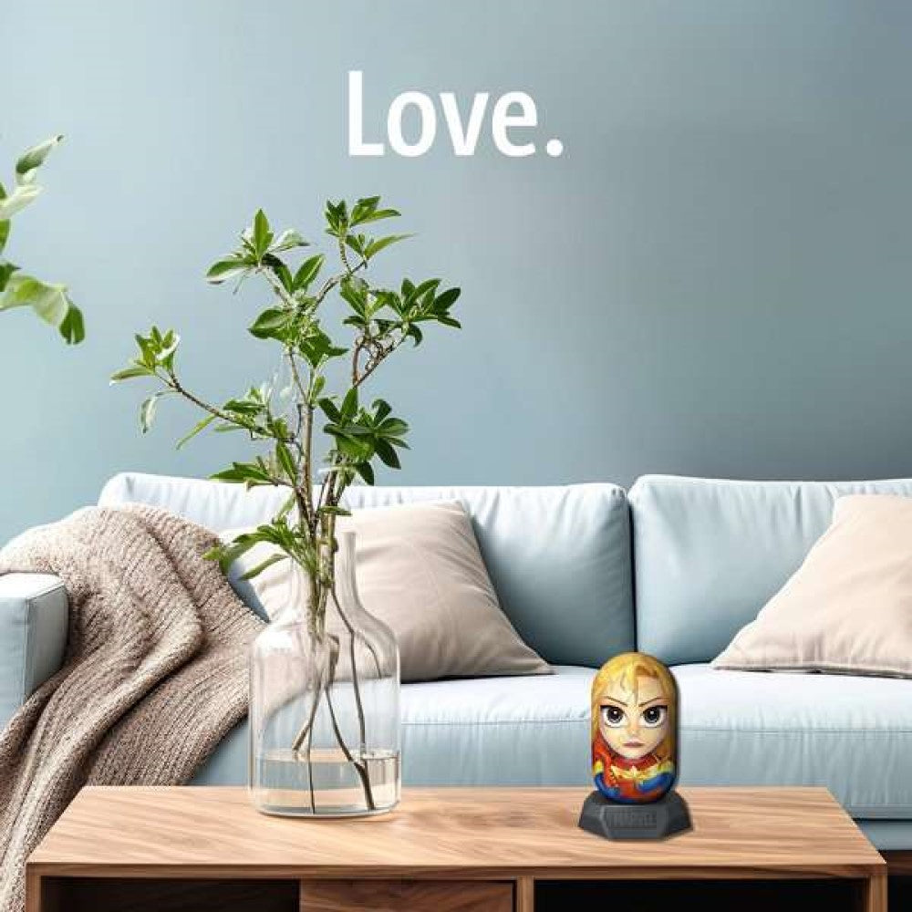 Captain Marvel figure on a coffee table in a living room with a light blue sofa, green plant, and "Love." on the wall
