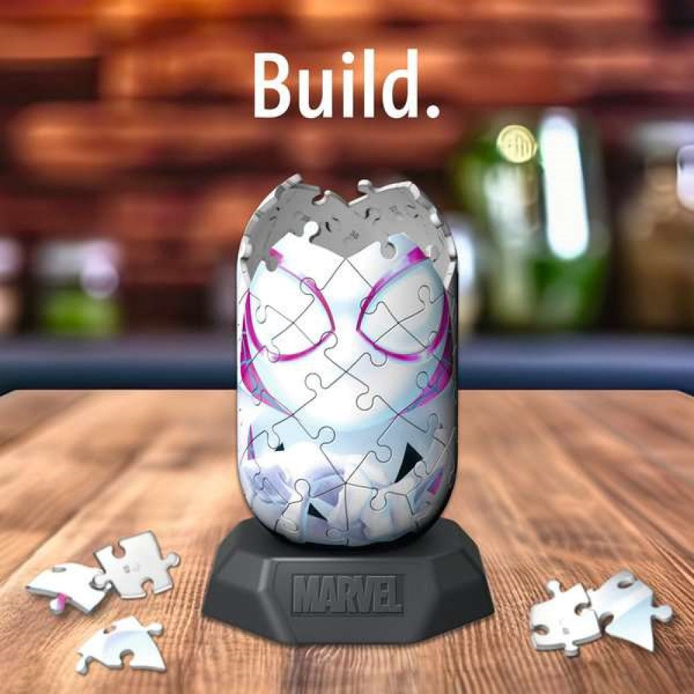 Partially built 3D Spider-Gwen mask puzzle on a Marvel stand, with scattered pieces. Text: Build