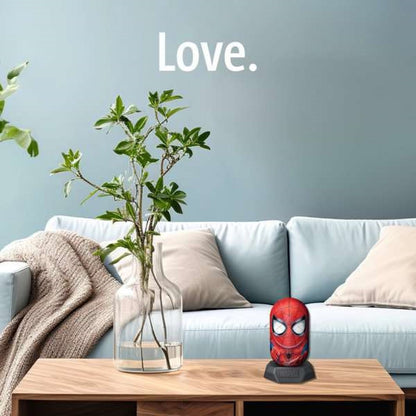 Spider-Man head figurine on a wooden coffee table in a living room, blue couch, plant, and 'Love.' text on wall