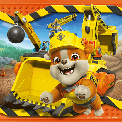 Smiling Rubble, the Paw Patrol construction pup, leaps forward in a hard hat with yellow heavy machinery behind him