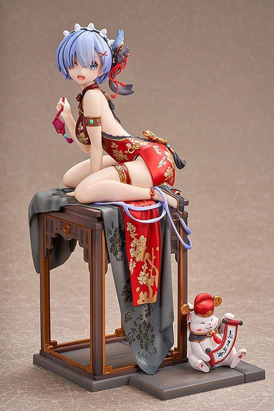 Anime figure kneeling in red Chinese dress on table, holding pouch, lucky cat figure nearby