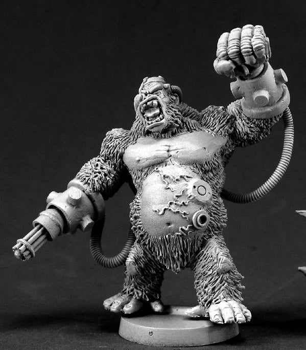 Black & white miniature of an aggressive cyborg gorilla with a gatling gun arm, raised mechanical fist, and hoses attached