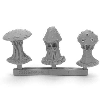Three unpainted grey Reaper fantasy mushroom miniatures on a sprue; one with a grotesque face