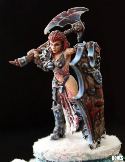 Painted miniature of a red-haired female barbarian with an axe and shield, standing on a snowy base.