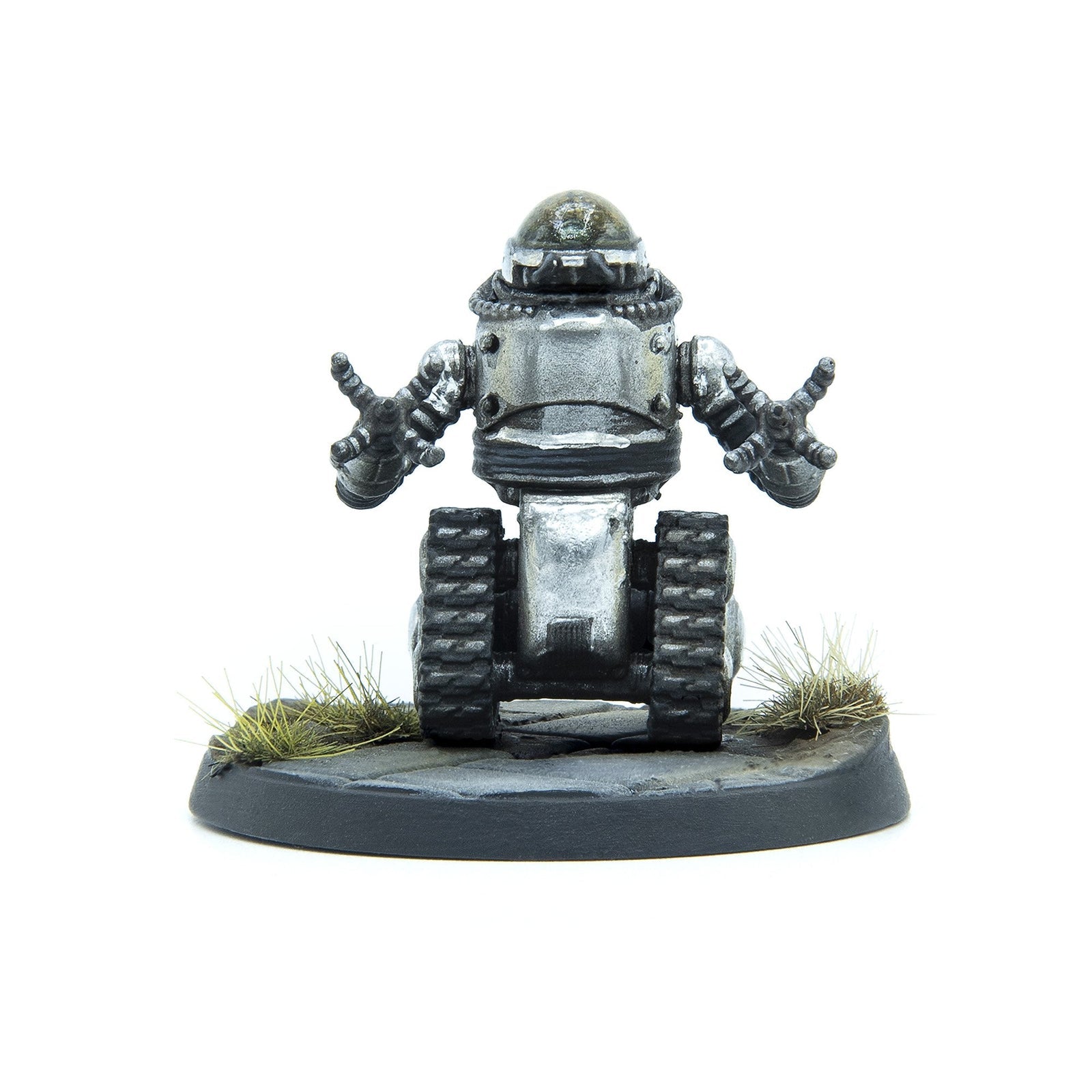 Silver robot miniature with a domed head, tank treads, and arms raised, on a dark grey base with grass tufts.
