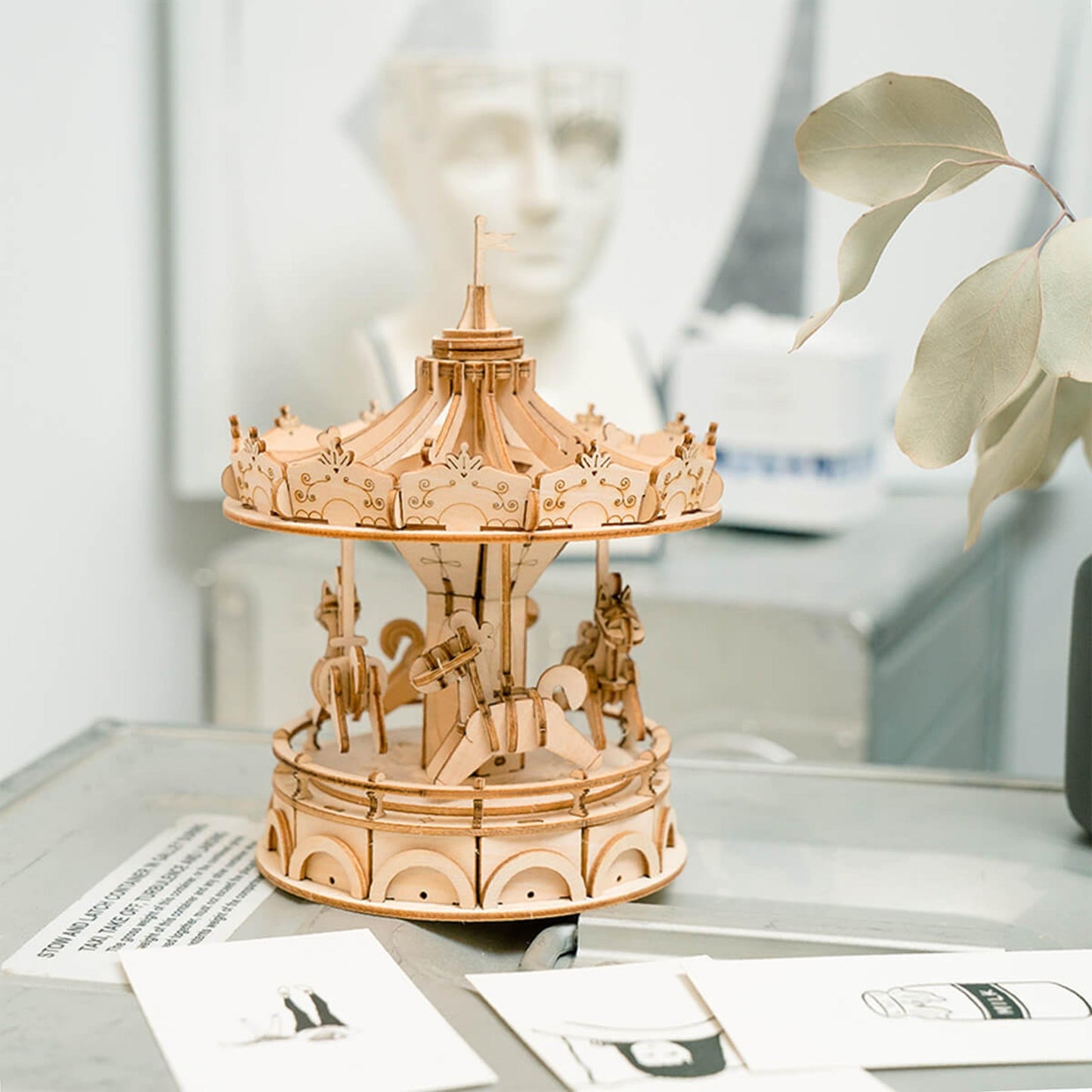 Intricate laser-cut wooden carousel model on a desk