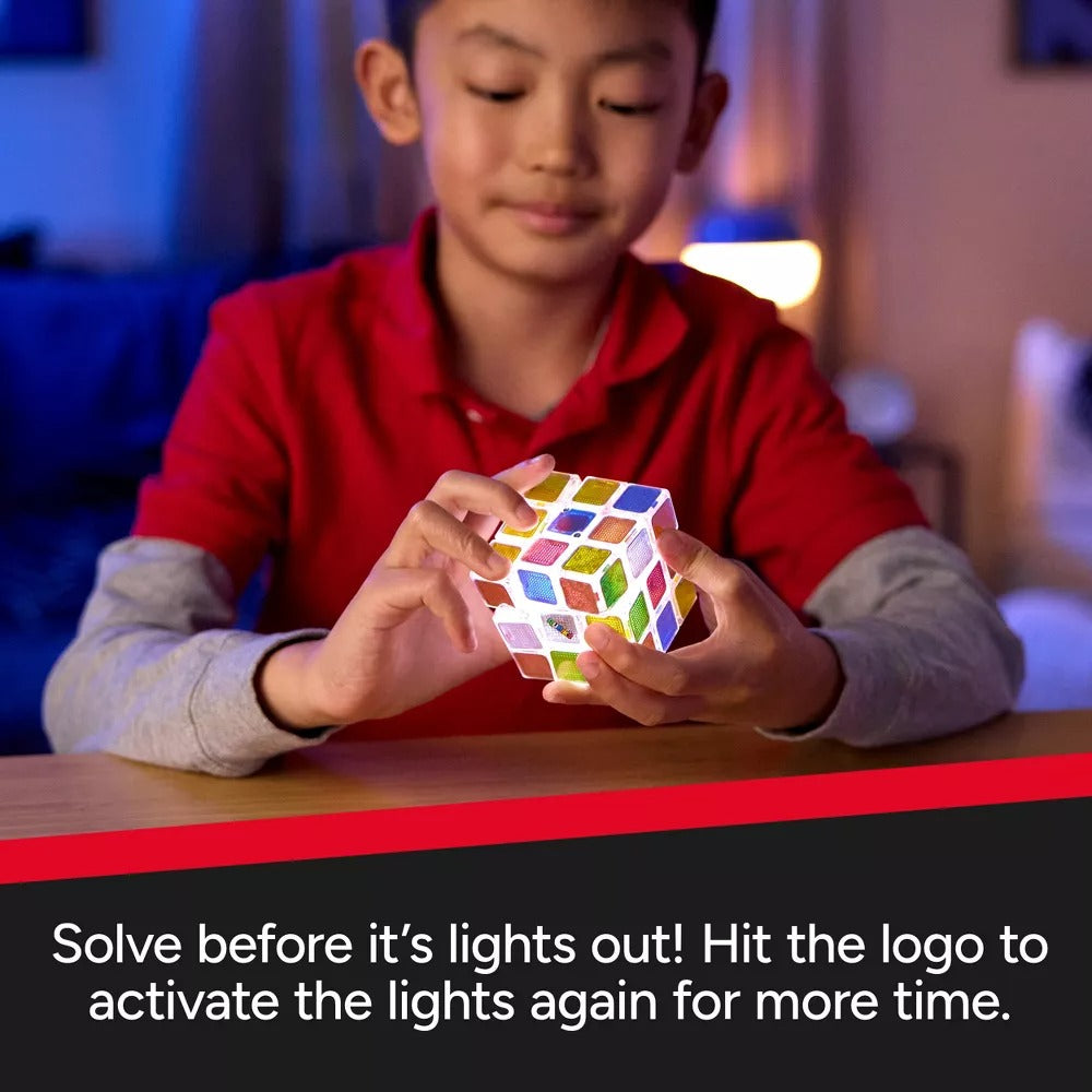 Young boy holding a glowing, multi-coloured Rubik's Cube puzzle in a dimly lit room
