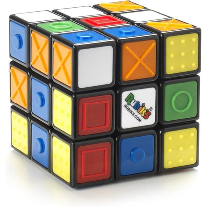 Rubik's Cube with coloured and textured tiles, including dots, crosses, circles, and raised buttons, white, red, blue, green, yellow, orange faces with black borders
