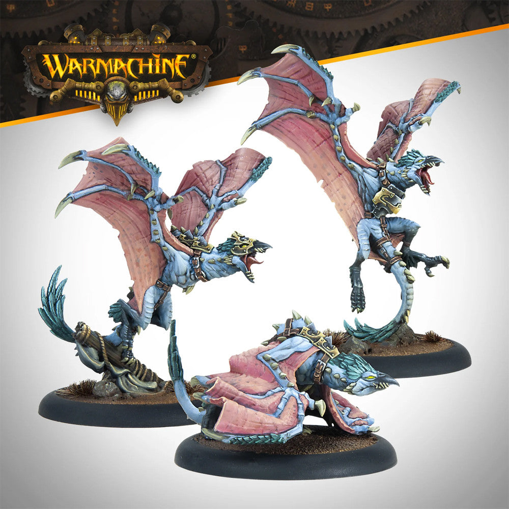 Three painted Warmachine miniatures: blue winged beasts with pink wings and gold armor, two flying, one crouching