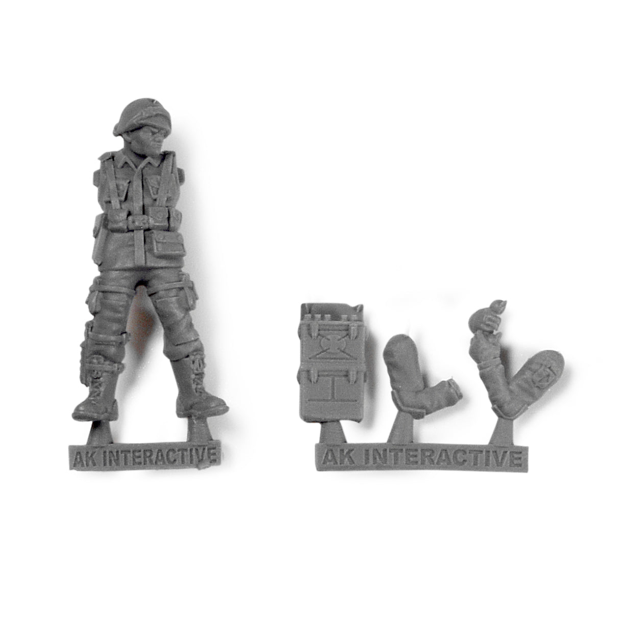 A grey plastic miniature figure of a soldier's torso and legs, with separate backpack and two arms on a white background