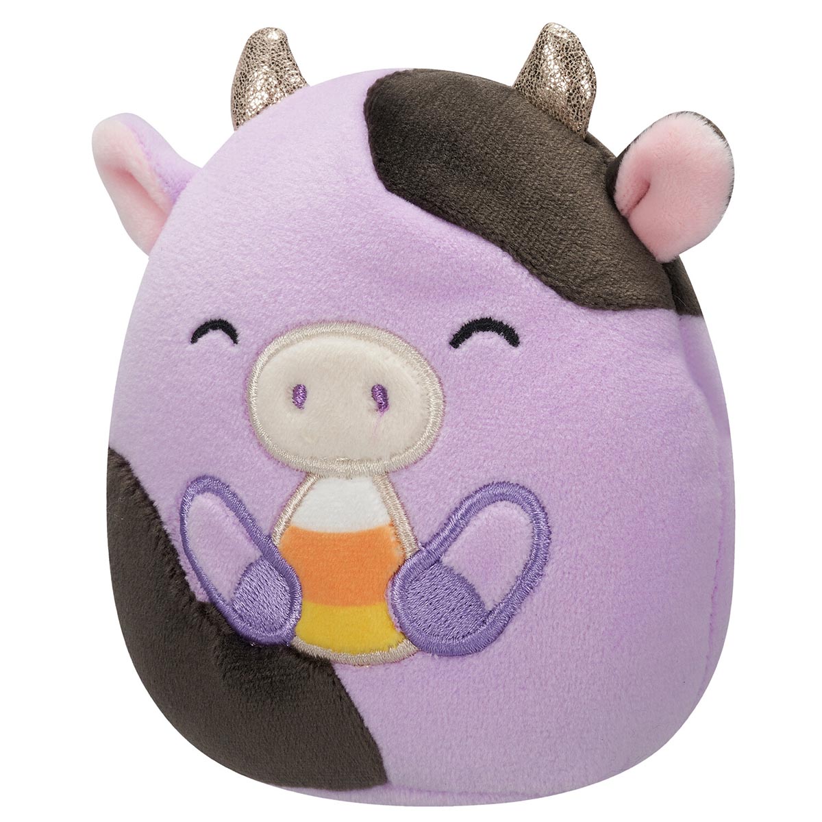A soft purple cow Squishmallow with brown patches, glittery gold horns, and a candy corn in its hands