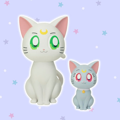 Two sitting Sailor Moon cat figures: white Artemis and light blue Luna, both with crescent moons, on a starry purple background