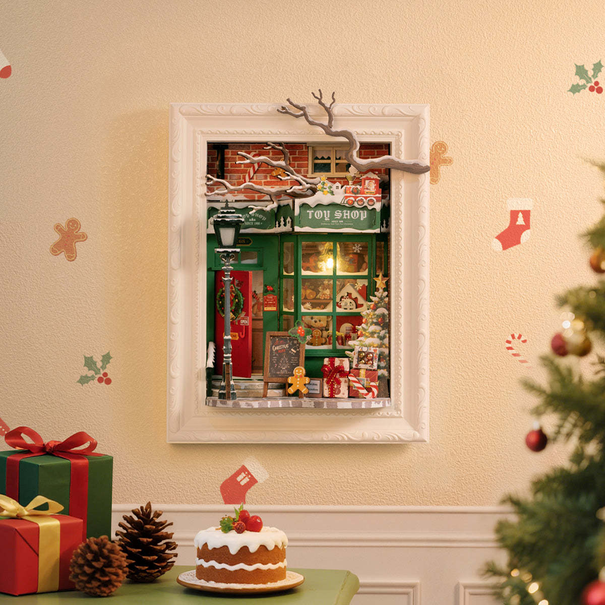 Framed miniature diorama of a green Christmas Toy Shop facade, with gifts and pinecones below