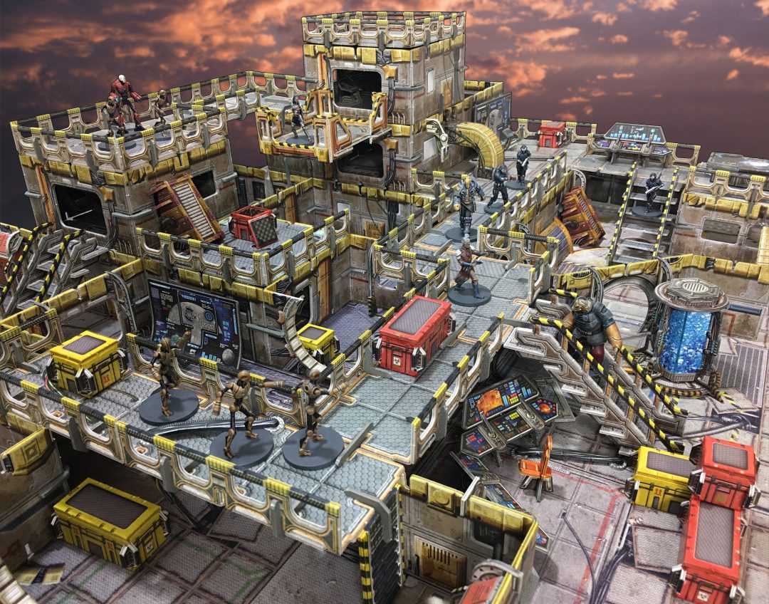 A complex sci-fi tabletop wargame layout with multi-level terrain and various soldier and robot miniatures in action under an orange sky.