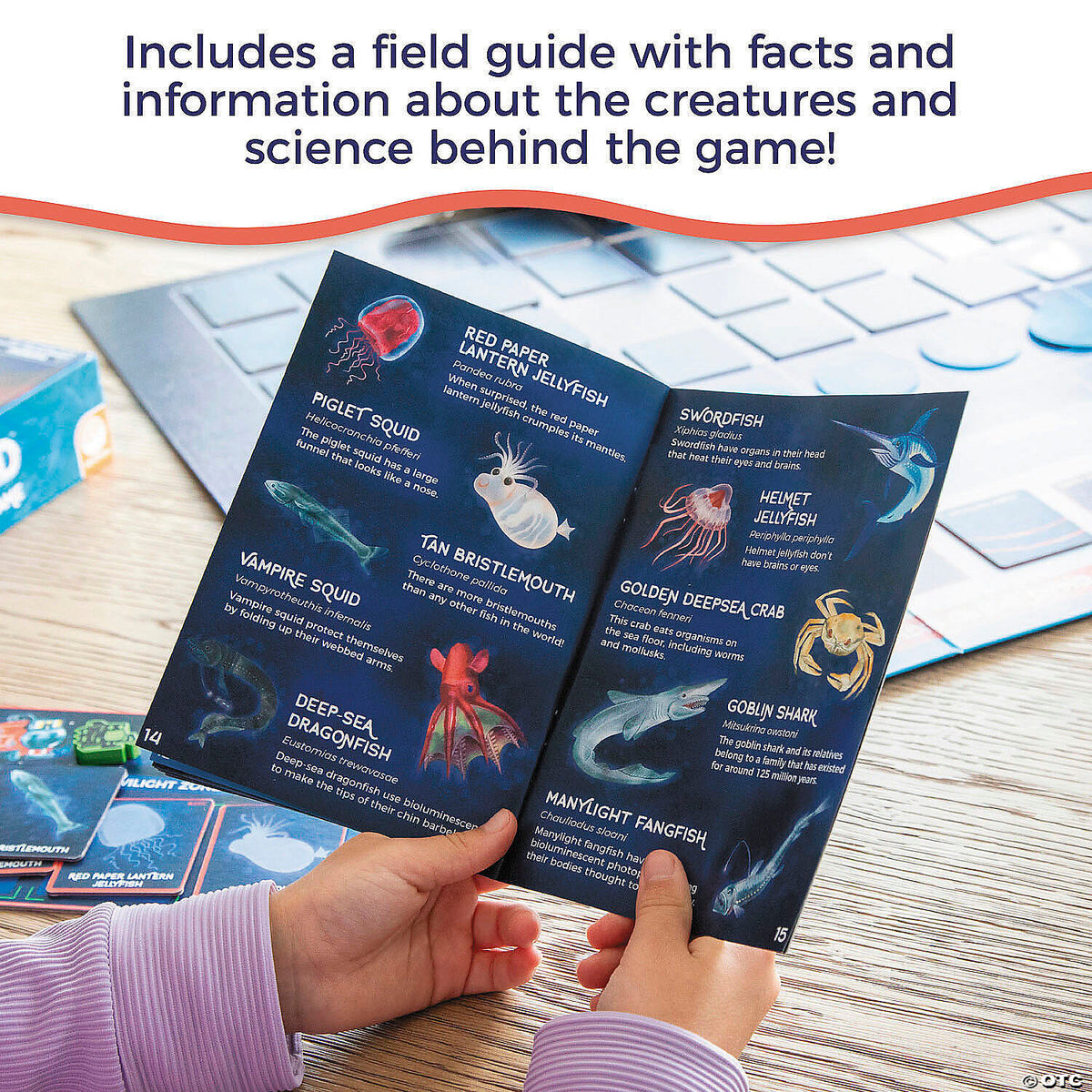Child holds an open game field guide displaying illustrations and facts about deep-sea creatures, with a game board nearby