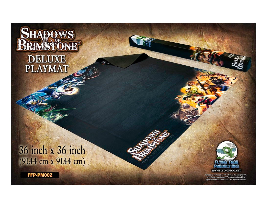 Shadows of Brimstone Deluxe Playmat, black with fantasy artwork along edges, partly unrolled next to its box.