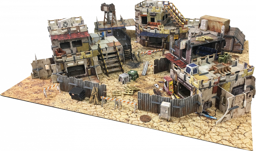 Miniature wasteland terrain: Multi-level, dilapidated buildings, scrap metal walls, and debris cover cracked earth.