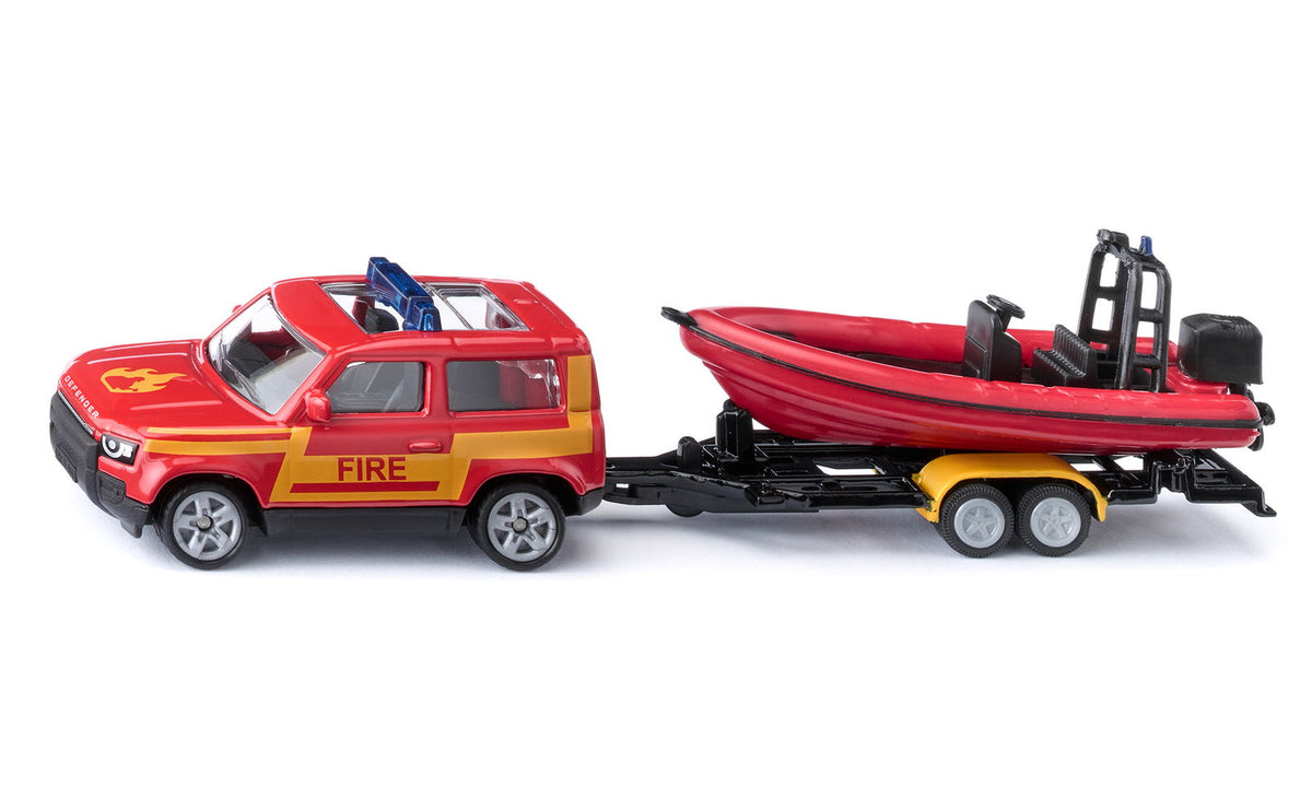 Red toy fire department Land Rover Defender with &quot;FIRE&quot; text, towing a red rescue boat on a trailer