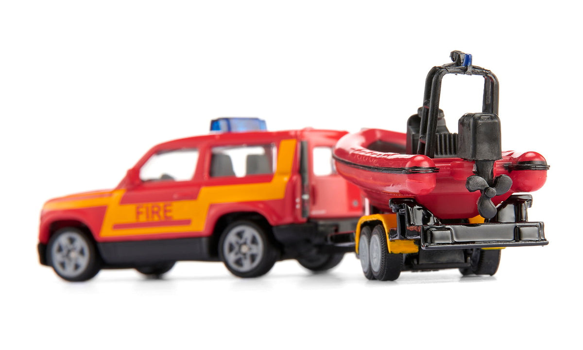 Toy fire Land Rover Defender towing a red inflatable rescue boat on a trailer