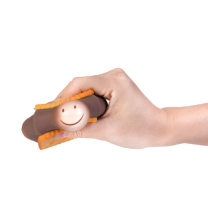 Hand squeezing a s'more-shaped stress toy with a smiley face marshmallow