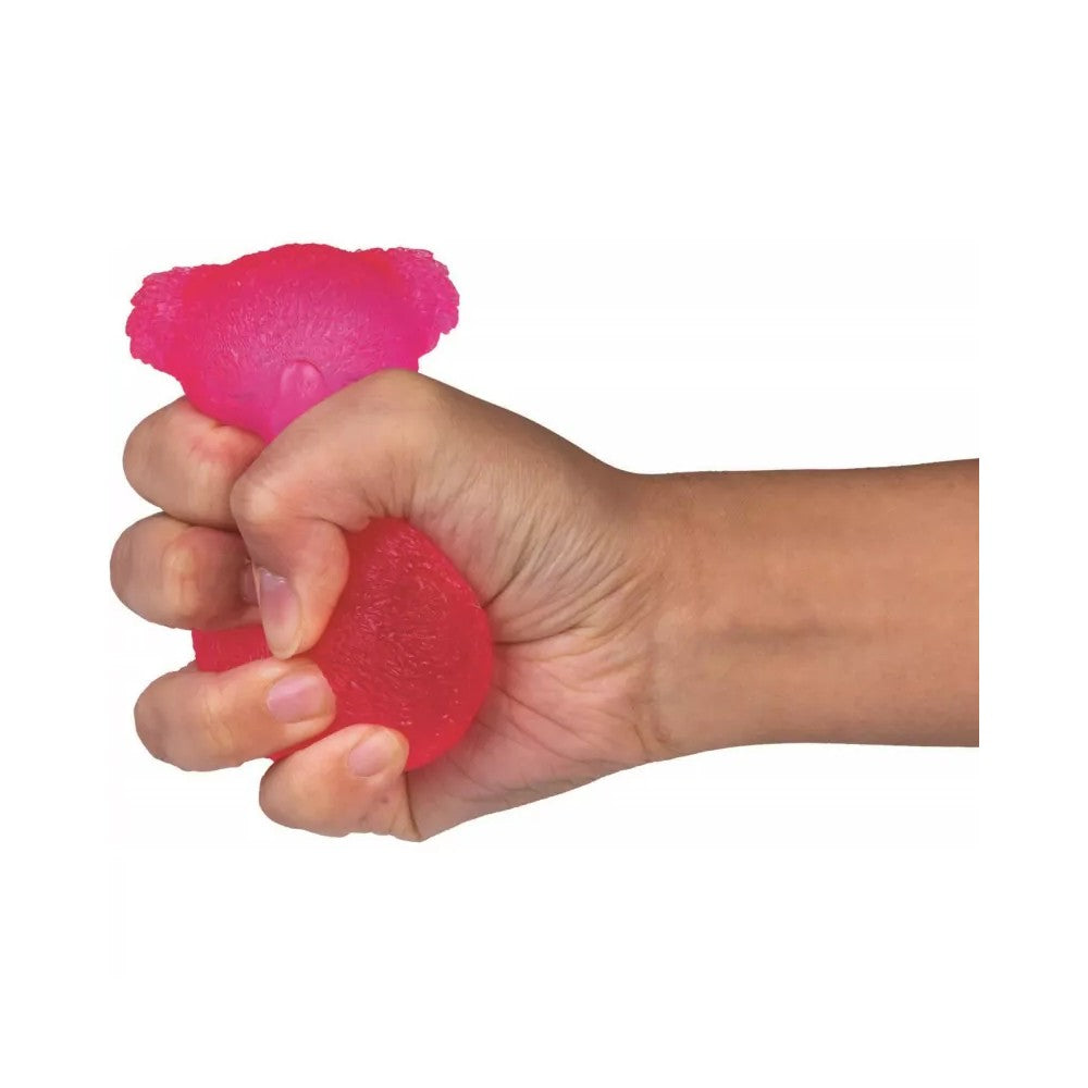 A hand squeezes a bright pink, textured squishy toy on a white background
