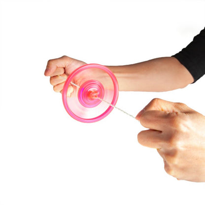 Hands spinning a translucent pink toy top by its string