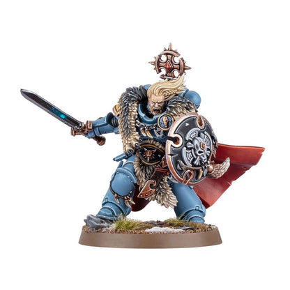 A miniature of a bare-faced, blue-armored warrior in fur, roaring, holding a glowing sword and round shield