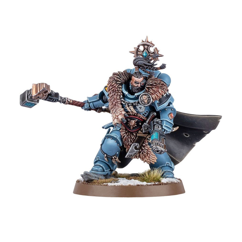 A blue armored, fur-clad Space Wolf in a dynamic pose, wielding a large golden hammer on a snowy base