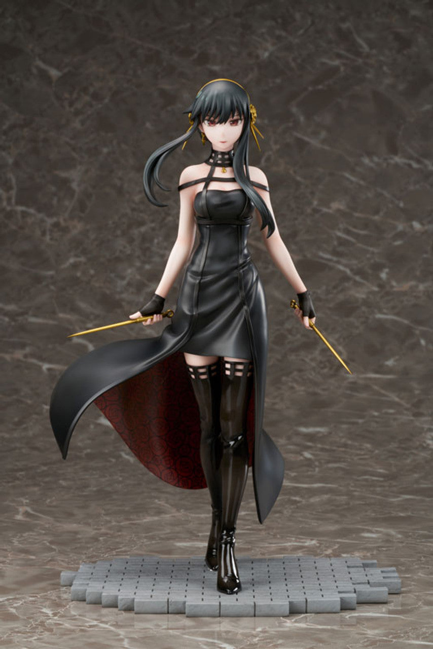 Yor Forger figure in a black strapless dress with a flowing cape, black boots, holding two golden stiletto weapons, standing on a textured gray base