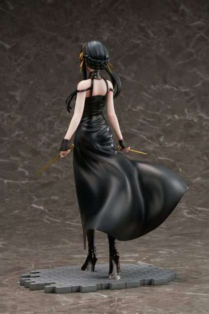 A Spy X Family Yor Forger figure seen from behind in a flowing black dress, holding a gold stiletto knife in each hand, on a grey base