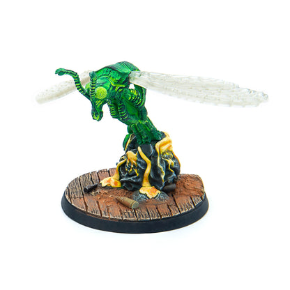 Bright green fly-like miniature with translucent wings emerging from a dark, lava-oozing base, with bullet casings