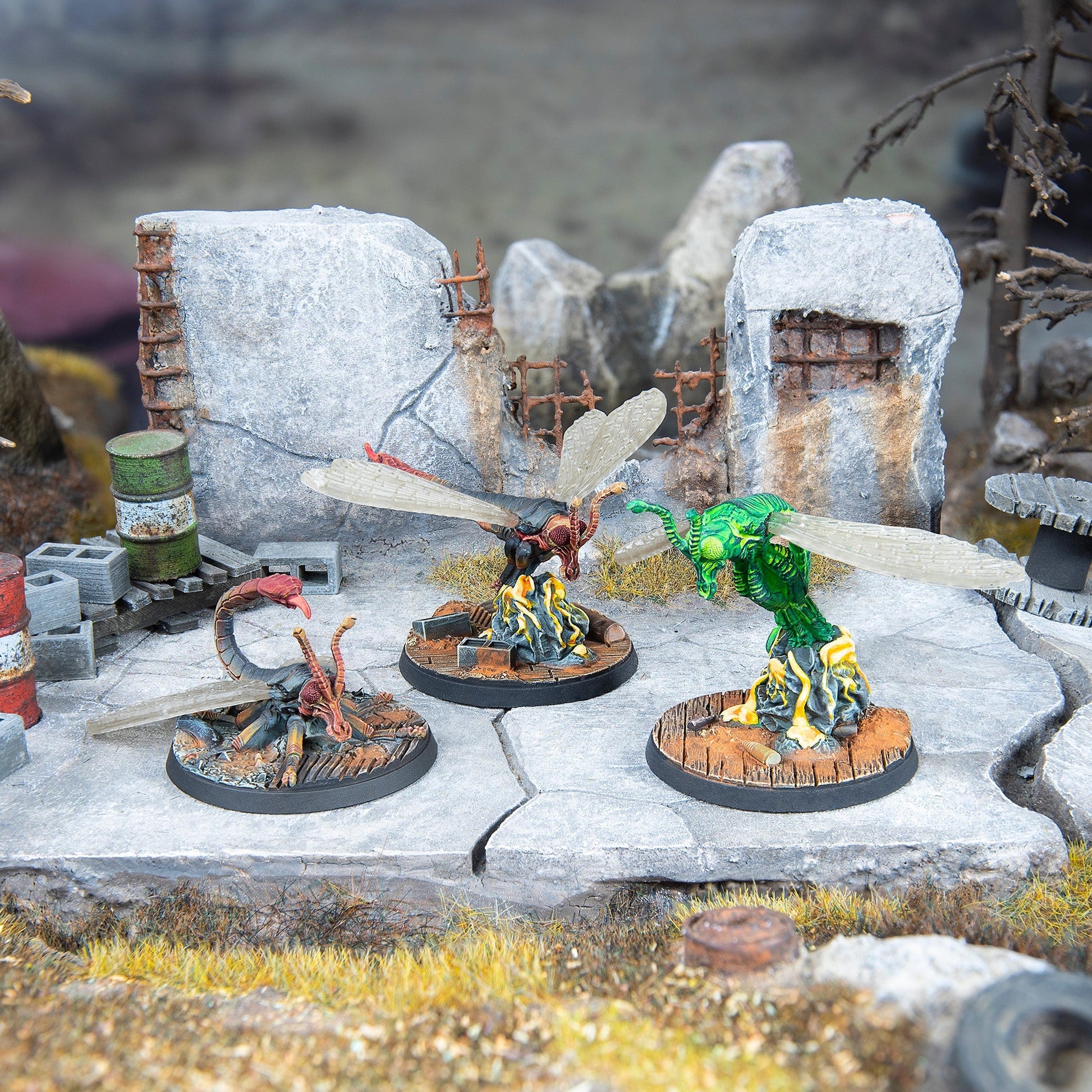 A green and a brown winged creature stand on yellow energy, while a third lies on the ground